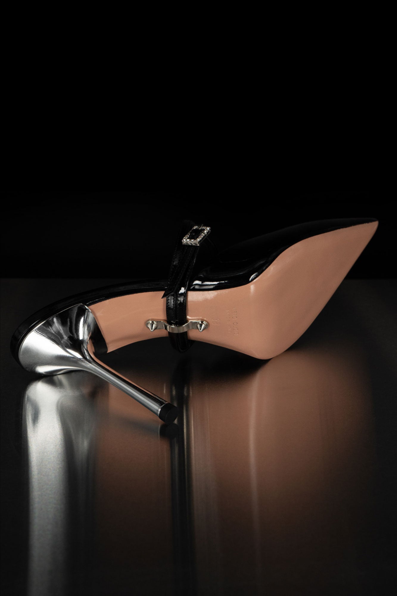 Black patent leather shoe with lacquered metallic heel and signature studded sole, symbol of Silvia Marson heritage and Italian craftsmanship
